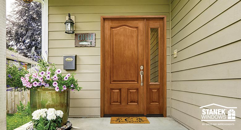 A solid wood entry door in a cherry finish with one sidelite on a home with tan siding. Entry Door